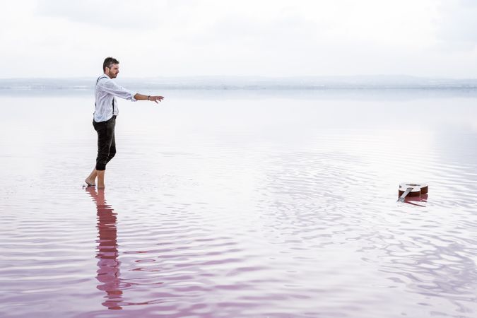 Modern man in wet shirt picking up guitar floating in water