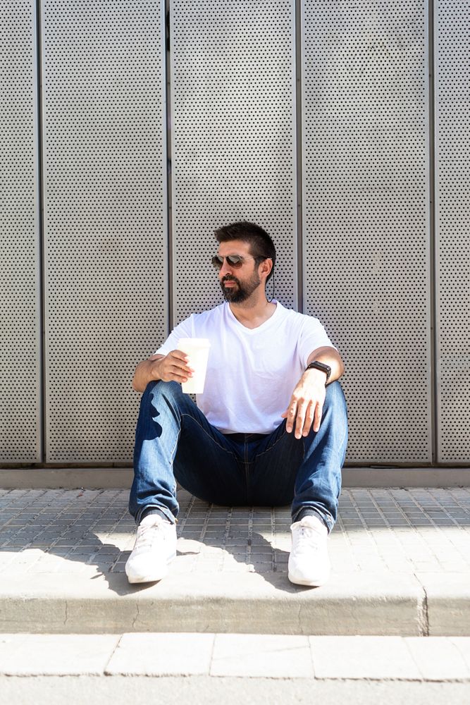 Latino man relaxing sitting outside with drink