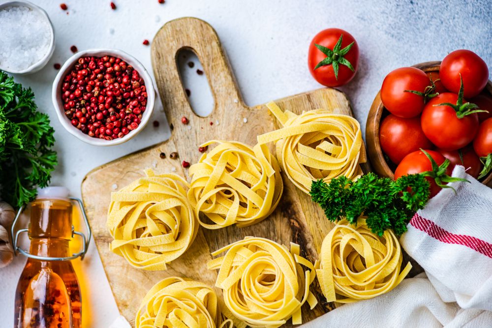 Ingredients for Italian pasta dish on breadboard with copy space
