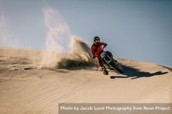 Dirt biker going full throttle over sand dunes 49OxE0