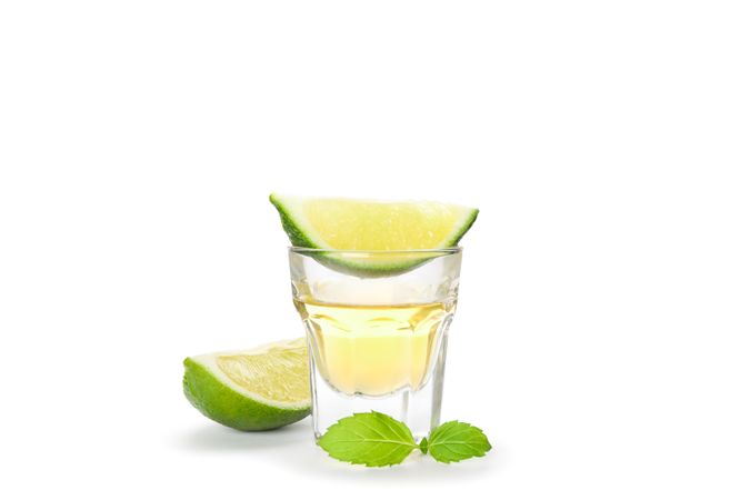 Tequila shot with lime slices and mint isolated on blank background