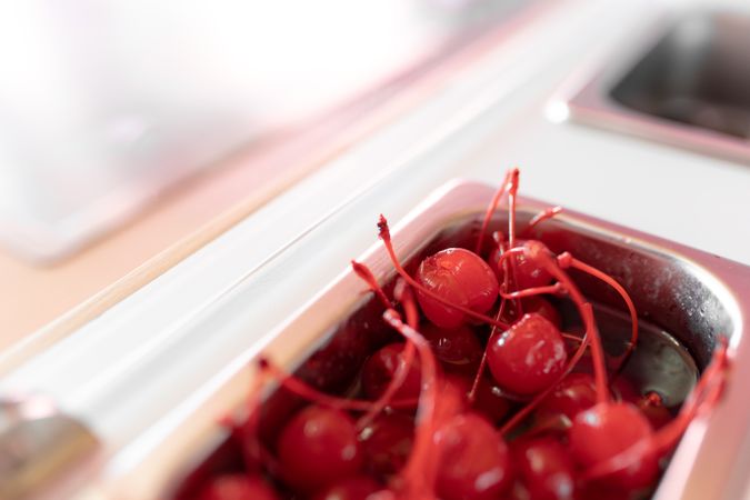 Close up photo of a metal tray filled with cherry toppings on an ice cream parlor counter