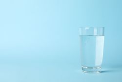 Full glass of water in light blue room