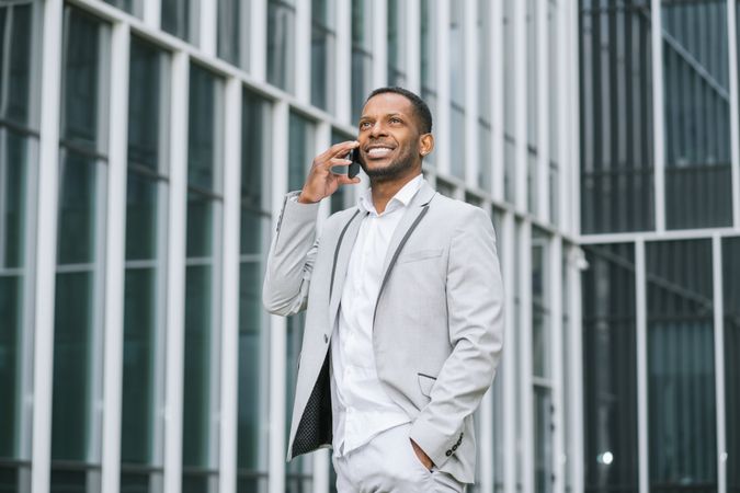 Elegant Black man talking smartphone near building