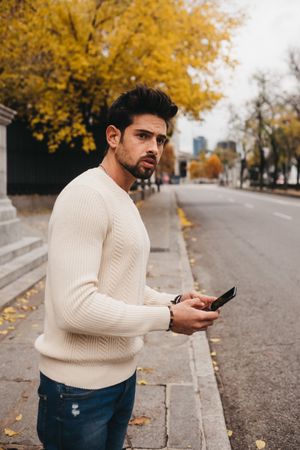 Young male hitchhiking with smartphone