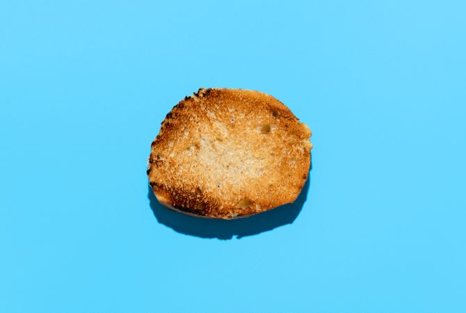 Toasted round bread slice above view on blue background