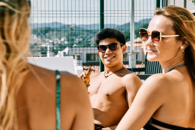 two young and women looking at a handsome man by the pool