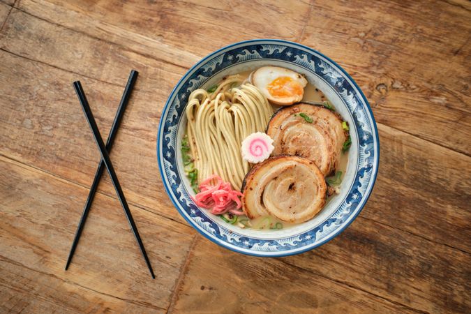 Bowl with delicious ramen soup on wooden table
