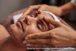 Beautiful woman relaxing with face massage at beauty spa 432gAx