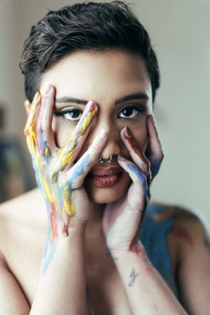 Woman with blue and yellow paint on hands covering her face