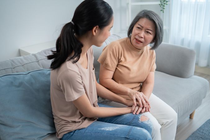 Asian mature mother having compassionate conversation with her daughter