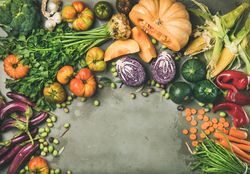 Fresh produce on concrete background, with halved squash, corn, cabbage, copy space