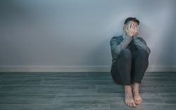 Man crying while covering his face with hands sitting on the floor