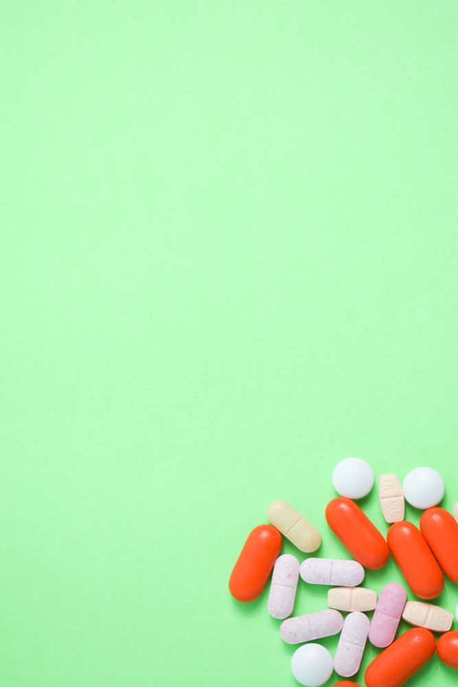 Top view of variety of medication and vitamins on green table with copy space