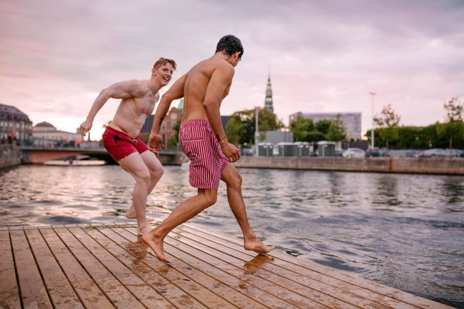 Young men running on a deck on a river in the city