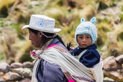 Peru - January, 02 2012: Peruvian woman carrying baby on back