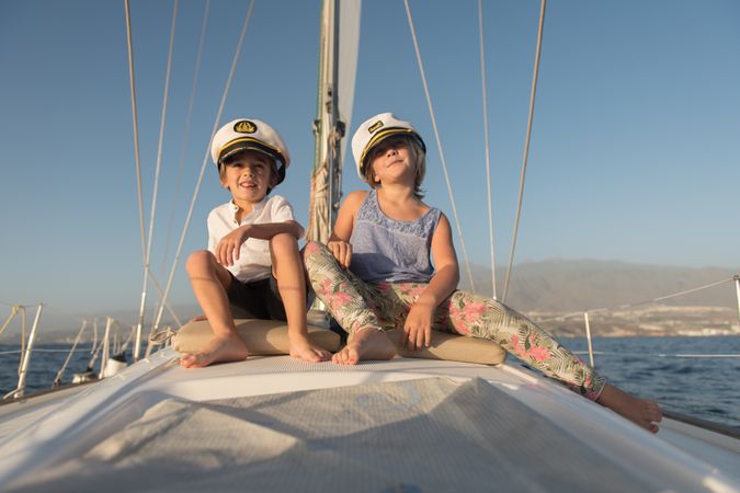 Smiling children sitting on deck of yacht in sea