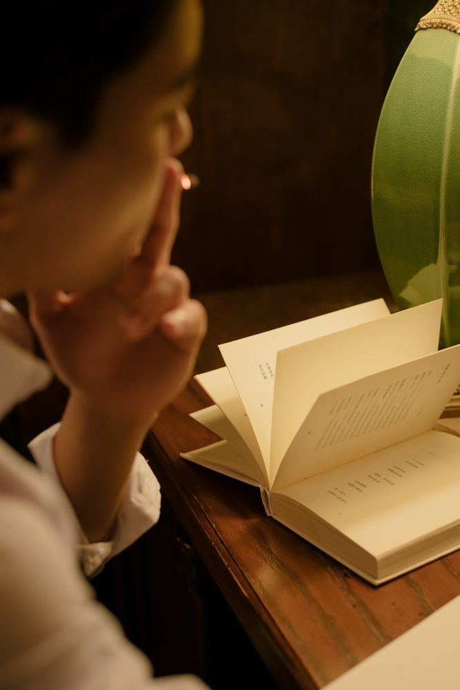 Back view of young person smoking and reading a book