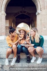 Happy diverse friends eating pizza on stairs in Italy 5rm730