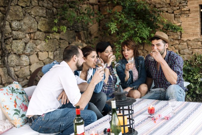 Group of friends sitting together and laughing while enjoying wine at a party