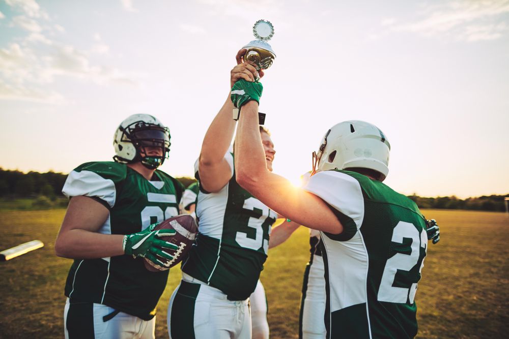 Men playing football holding up trophy