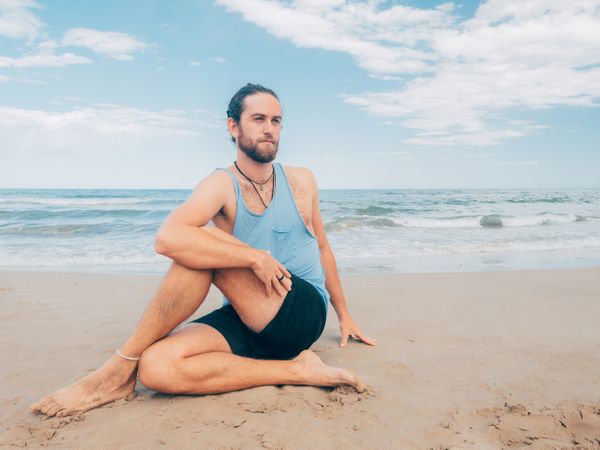 Man training yoga on beach