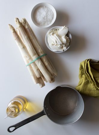Saucepan and napkin near asparagus and condiments