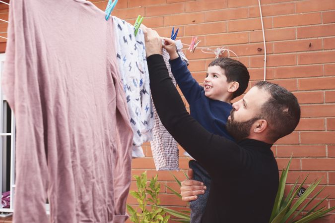 Father and son hanging clothes on rope