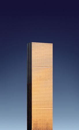 Tall building reflecting a bright light against a dark blue sky