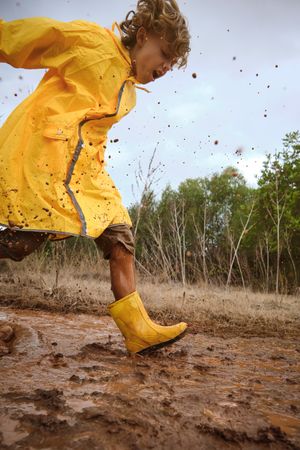 Preteen boy playing in mud in nature