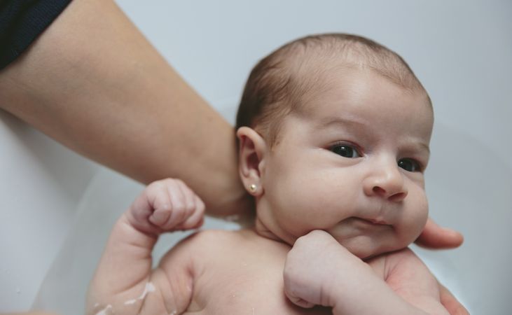 Newborn in the bathtub held by her mother