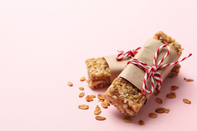 Tasty granola bars on pink background, close up