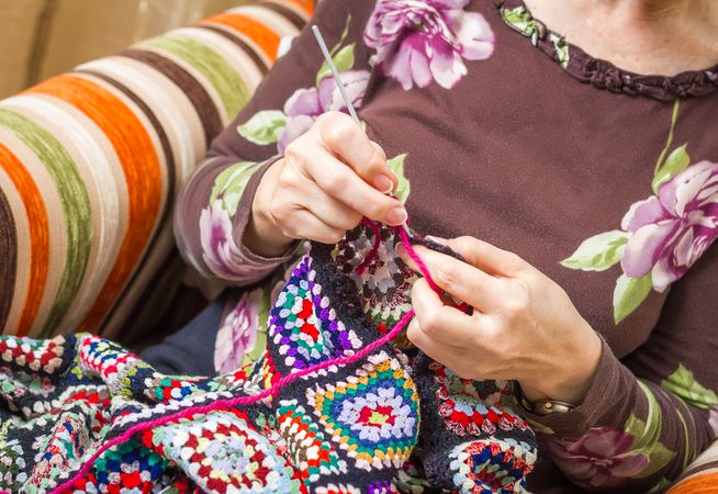 Hands of woman knitting a vintage wool quilt