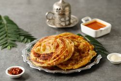 Plate of roti parata or roti canai with sauce and tea