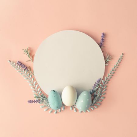 Creative layout made with spring flowers, eggs and leaves on pastel pink background