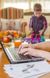 Woman hands writing in notebook and boy playing