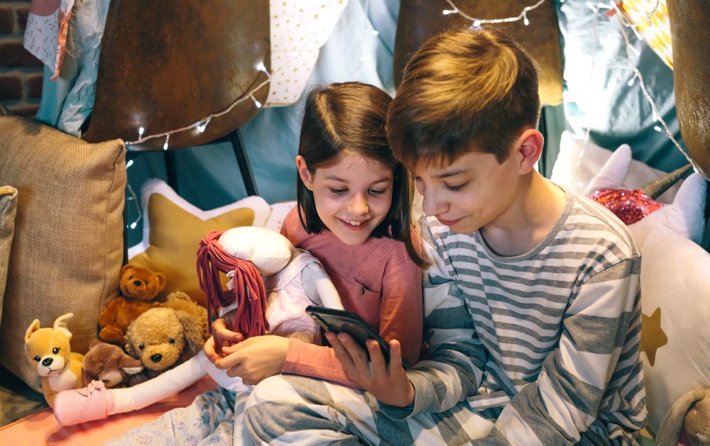 Portrait of smiling children looking mobile phone while chatting on social media application sitting