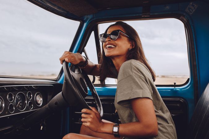 Portrait of happy young woman driving a car and smiling