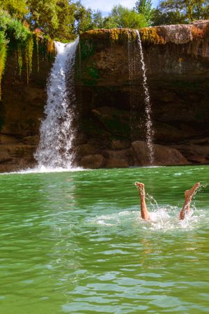 Legs in clean water near waterfall
