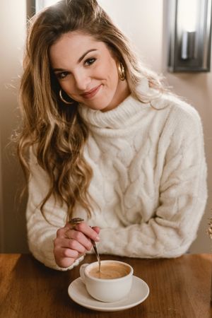 Elegant woman mixing coffee in cafe