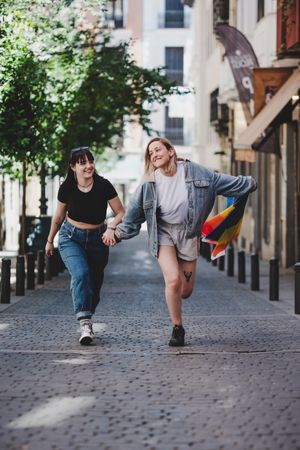 Lesbian couple with LGBT flag walking on street