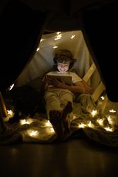 Cheerful boy watching video in blanket fort