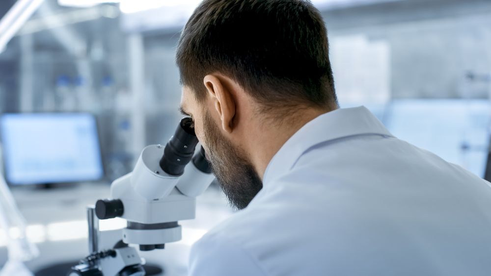 Over the Shoulder View of a Research Scientist Looking into Microscope.