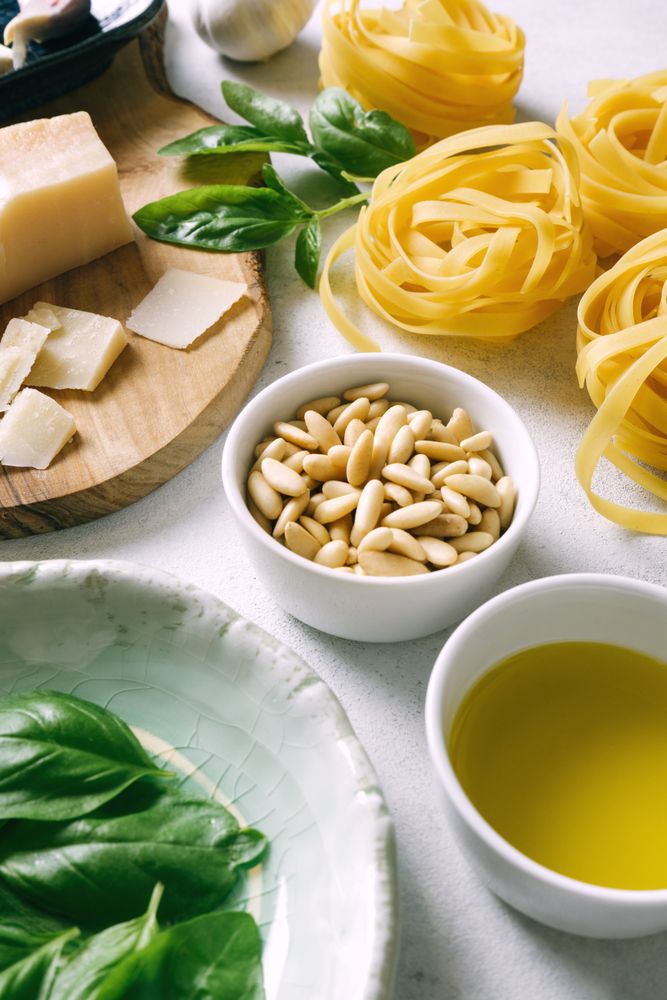 Basil leaves and ingredients for pesto sauce on plates on table