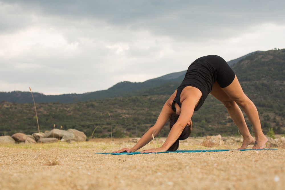 Woman practicing yoga outdoors near water
