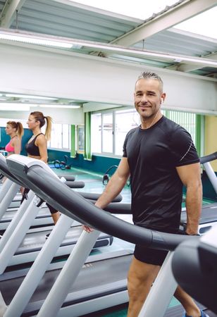 Portrait of smiling fit male on treadmill in gym