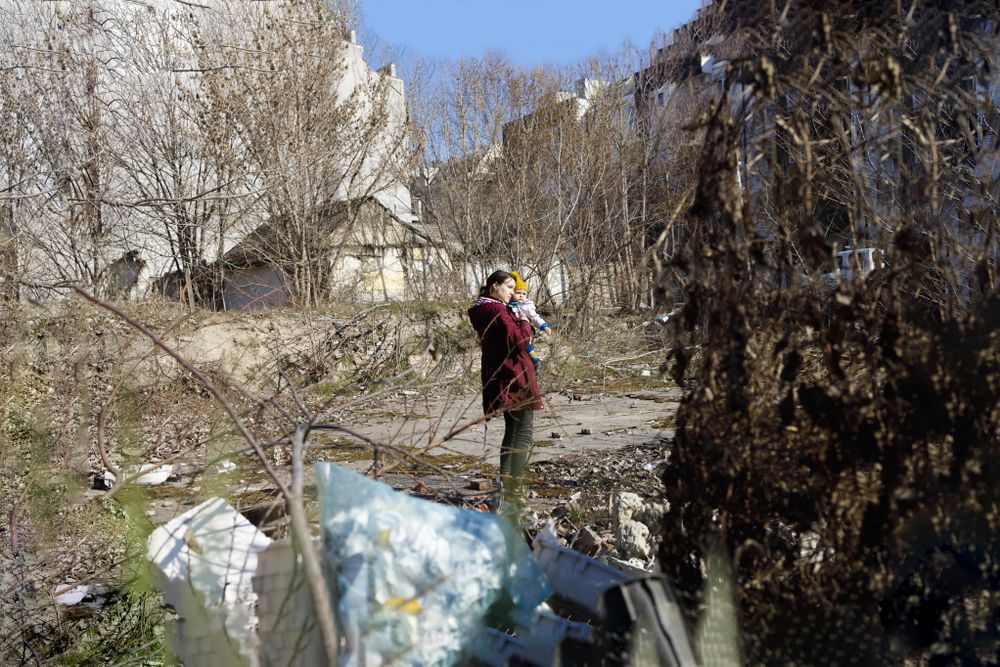 Woman holding her baby in garbage filled clearing
