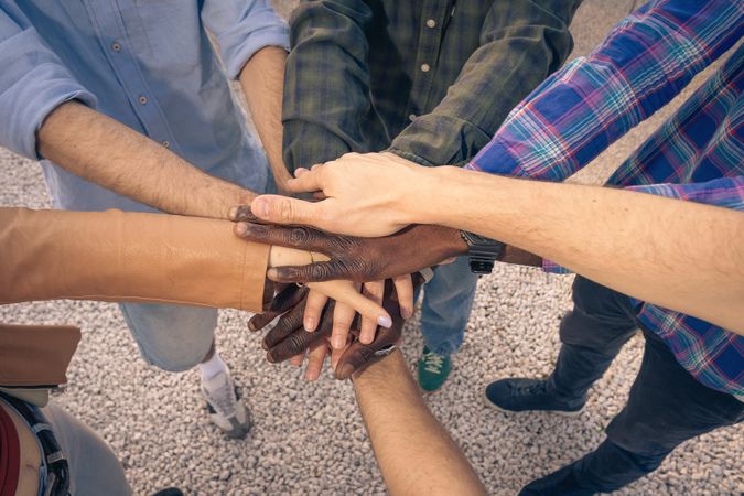 Top view of diverse people stacking their hands together in a show of unity.