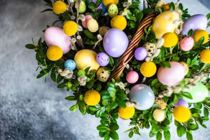 Top view of pastel Easter eggs & flowers in decorative basket