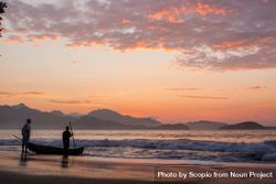 Silhouette of two men standing beside boat on seashore during sunset 49EkW4